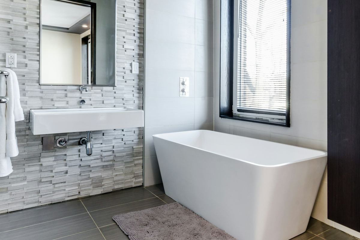 A clean, bright bathroom with a white bathtub and basin