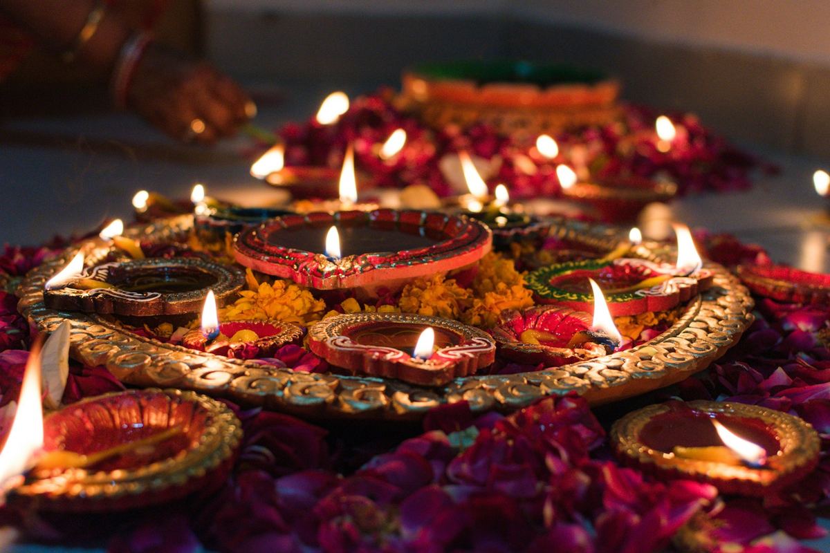 Lit Diwali diyas on a decorated tray with flower petals
